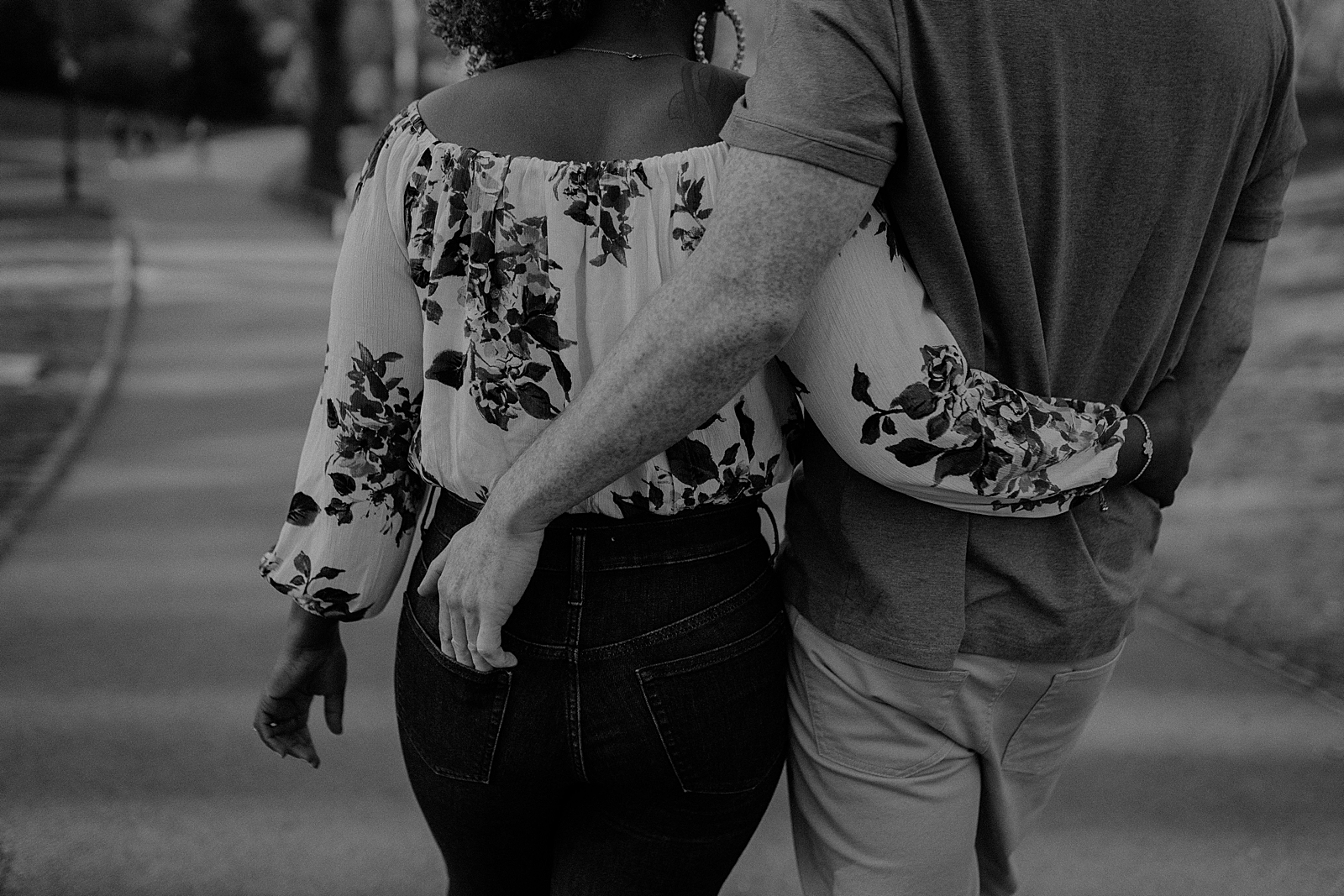B&W Couple with arms around each other walking on sidewalk