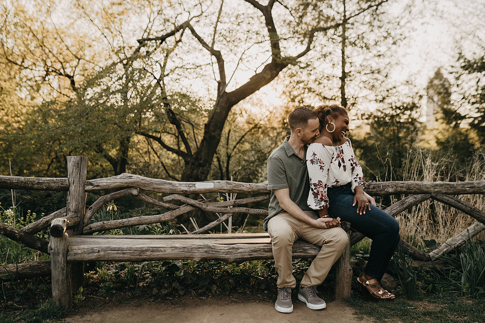 Woman sitting on man's lap on and and man nuzzling on shoulder of woman wooden bench