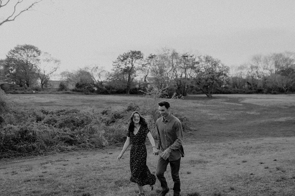 B&W couple holding hands and walking on field together