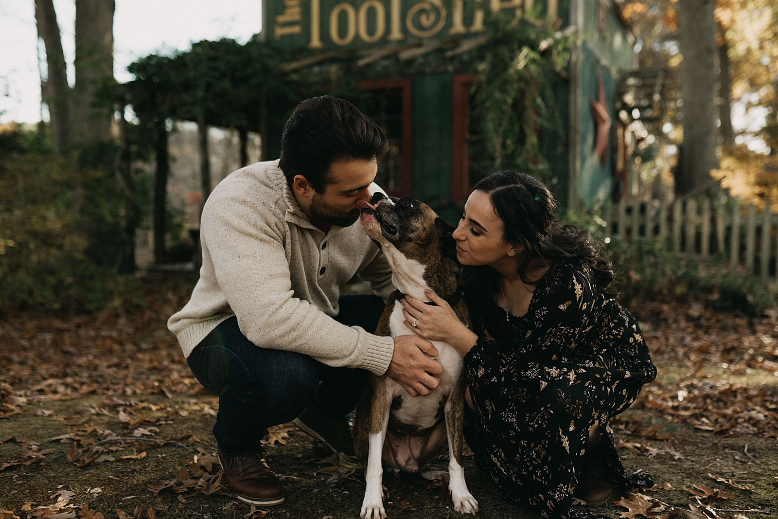 Couple leaning down to pet dog and dog licking man on nose