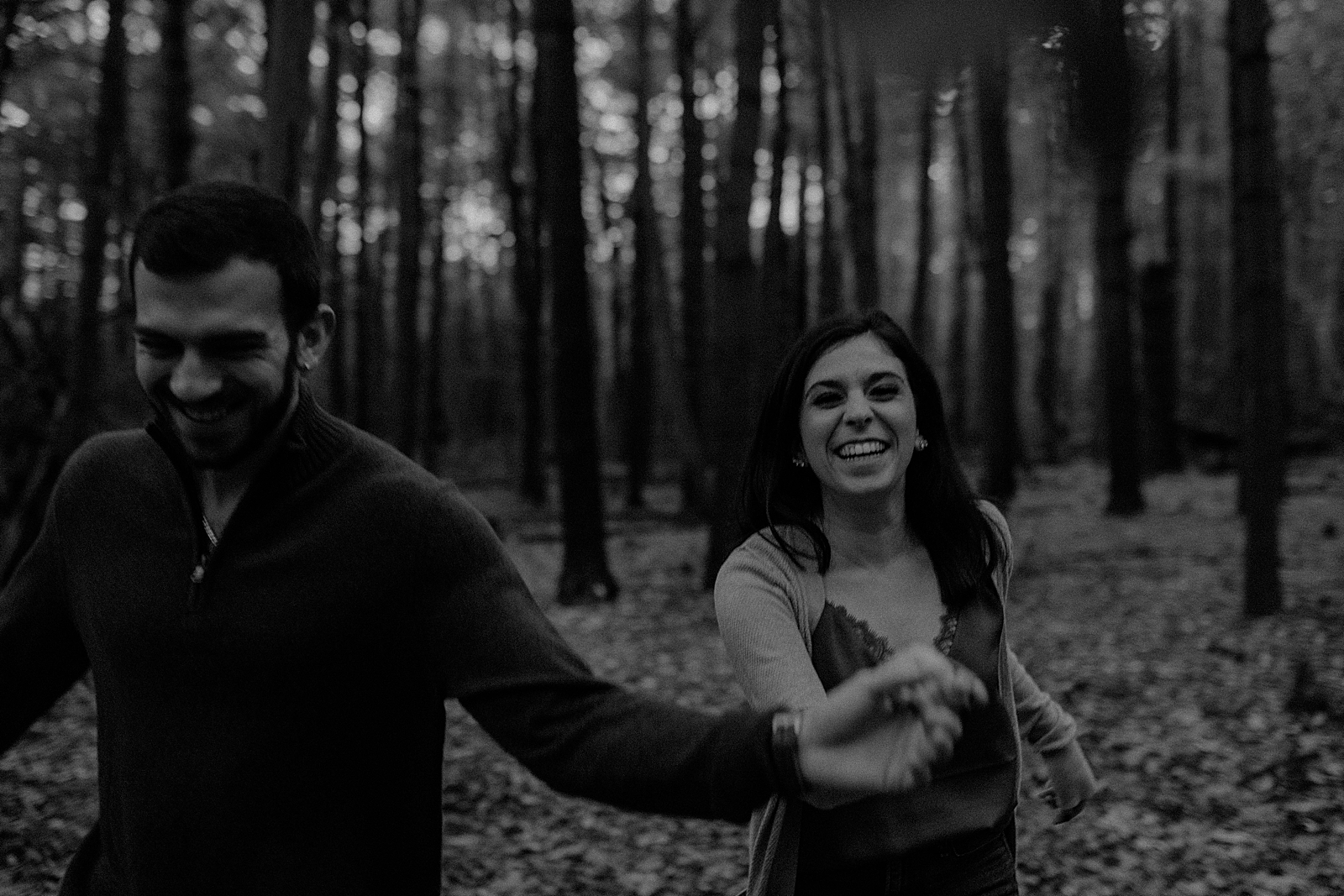 B&W Couple holding hands and walking through forest together