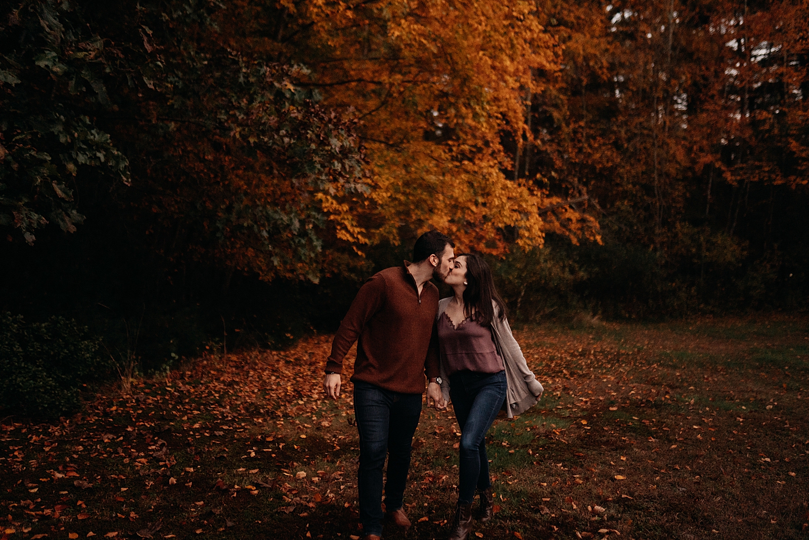 Couple kissing and walking in fallen leaf forest