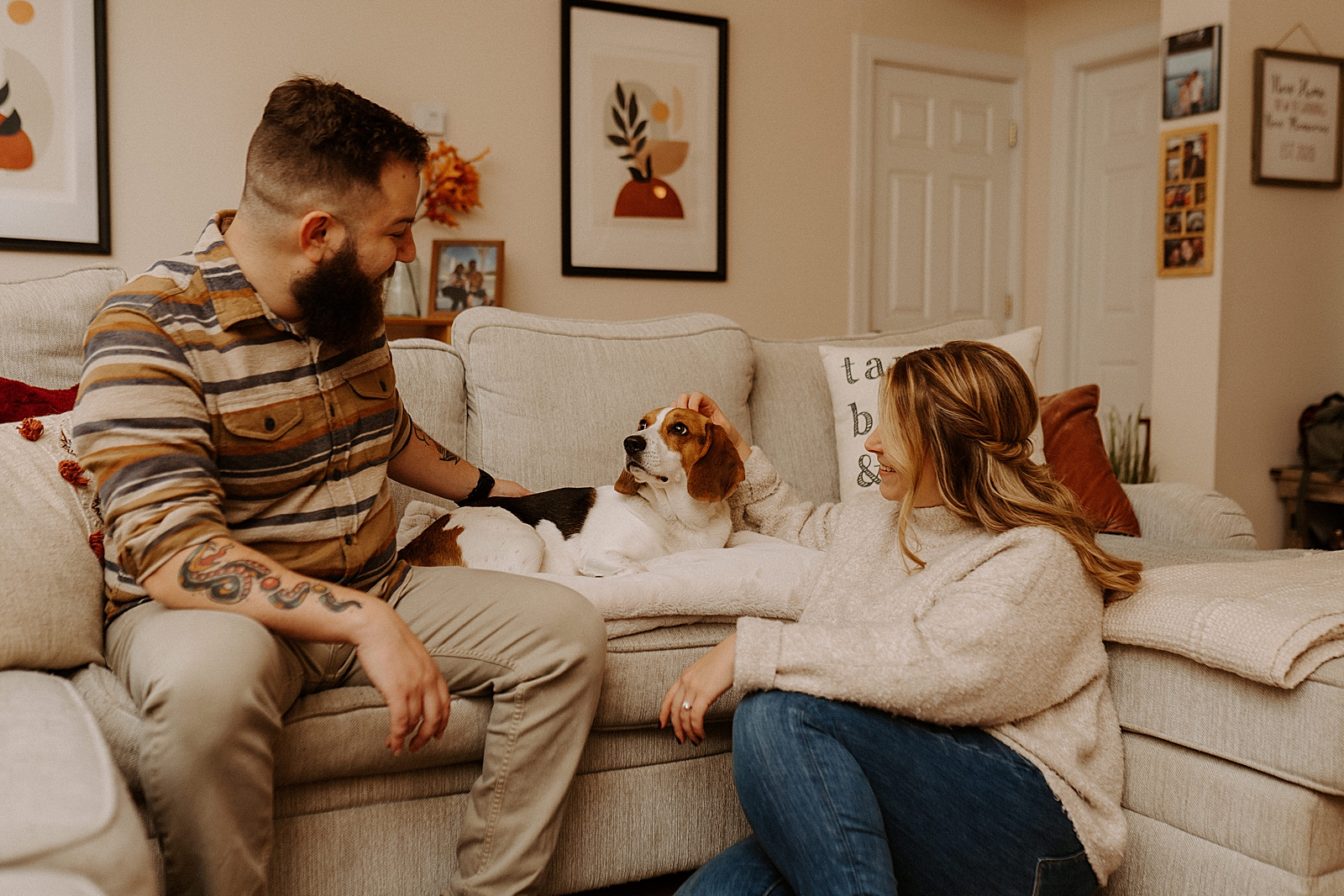 Couple on living room couch petting dog