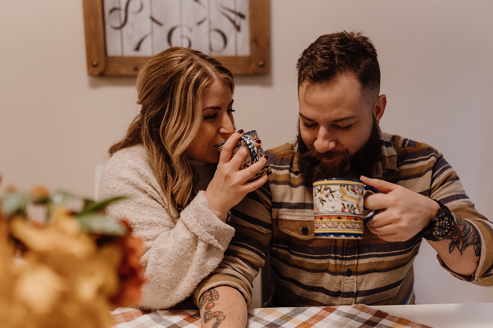 Couple sitting together at table and drinking out of mugs