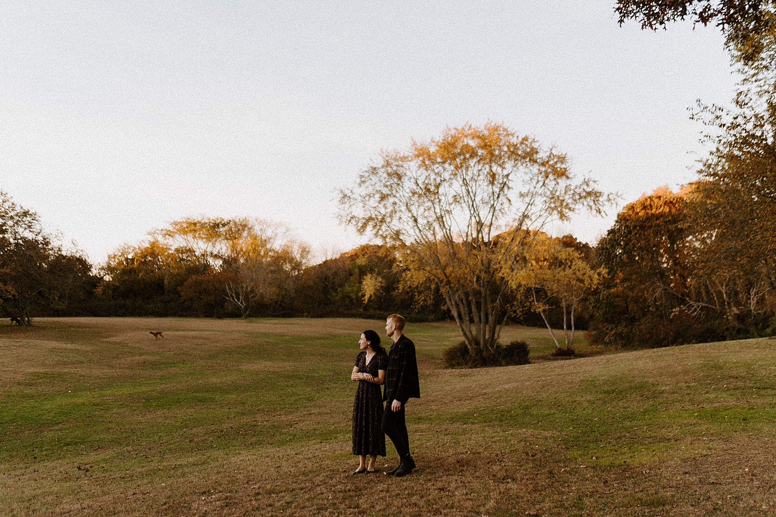 Wide shot of couple looking into the distance on green field