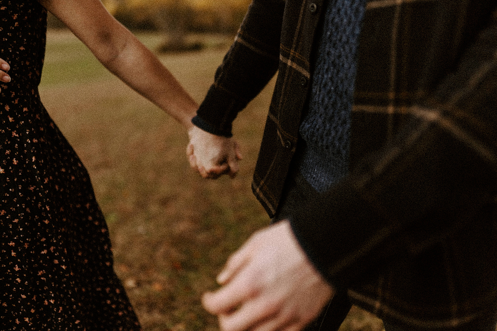 Closeup of couple holding hands on field