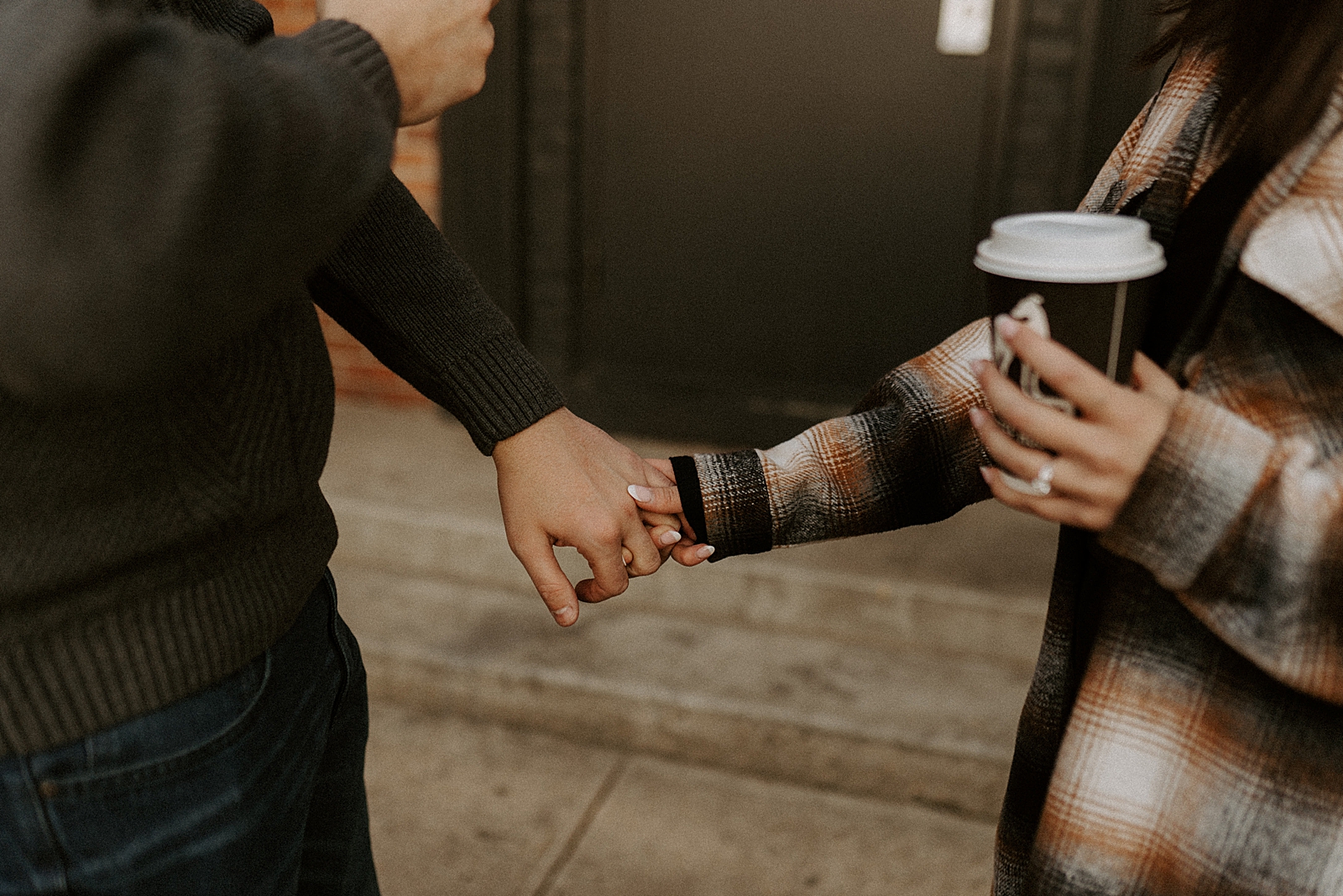 Closeup of couple extending arms and holding hands on sidewalk