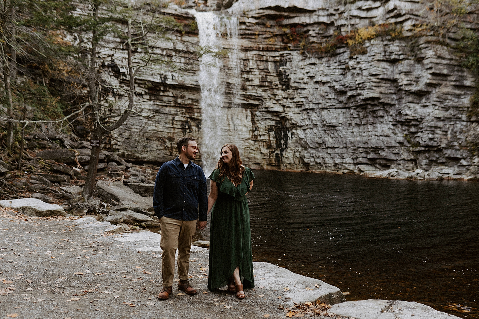 Couple standing together in front of waterfall