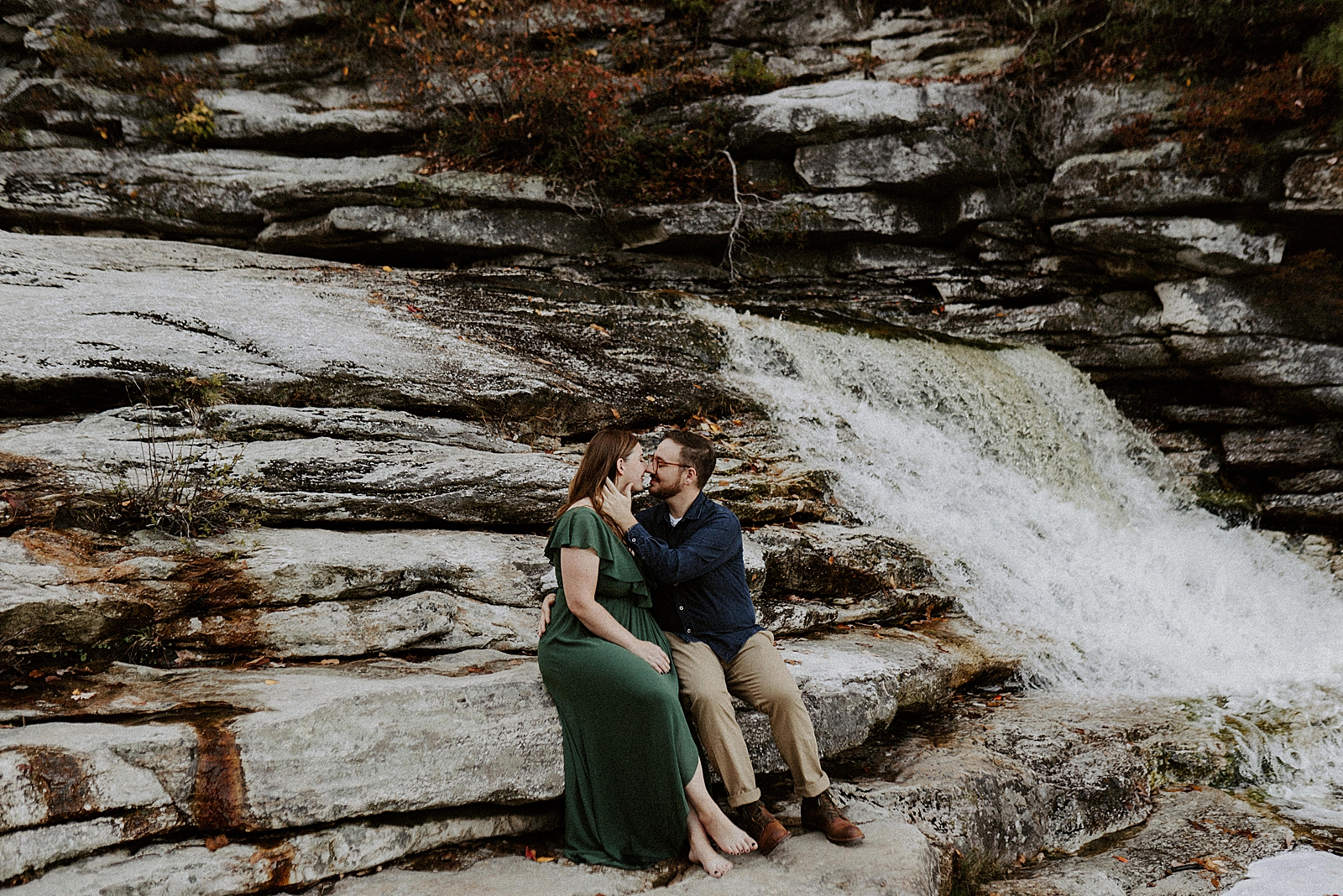 Couple sitting together on stone formation and kissing
